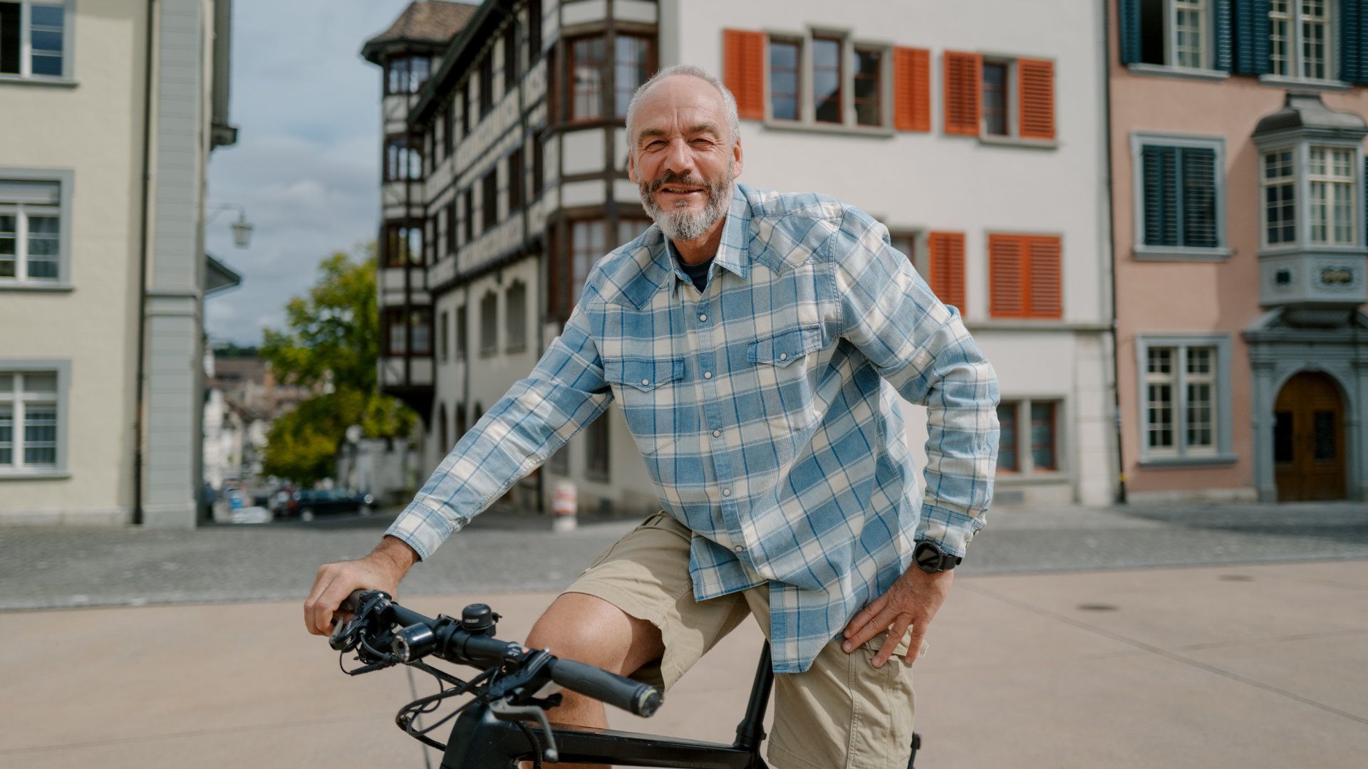 Ein Mann mit Bart fährt in einer Stadt Fahrrad.