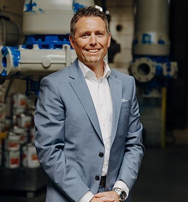 Rolf Schweizer, CEO of  Hidrostal, in einem Anzug und einem weissen Shirt steht vor einer Maschine.