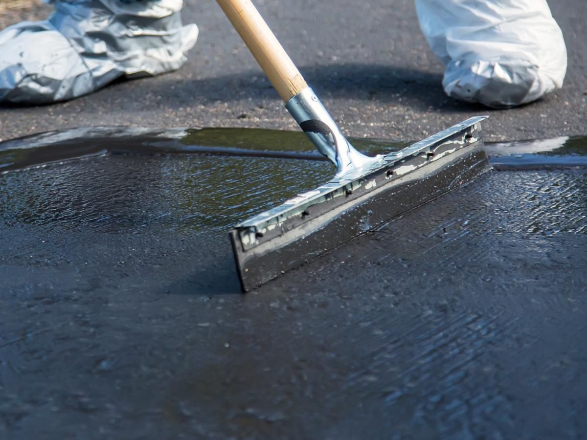 Jimmy's External Cleaning Services applying the first coat of a driveway sealer on a concrete driveway
