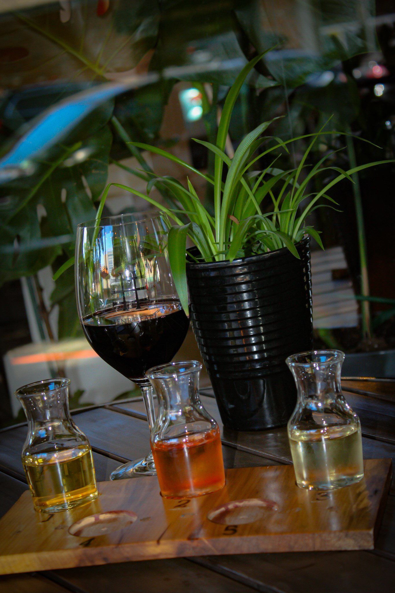 A wooden table topped with bottles of liquid and a glass of wine.