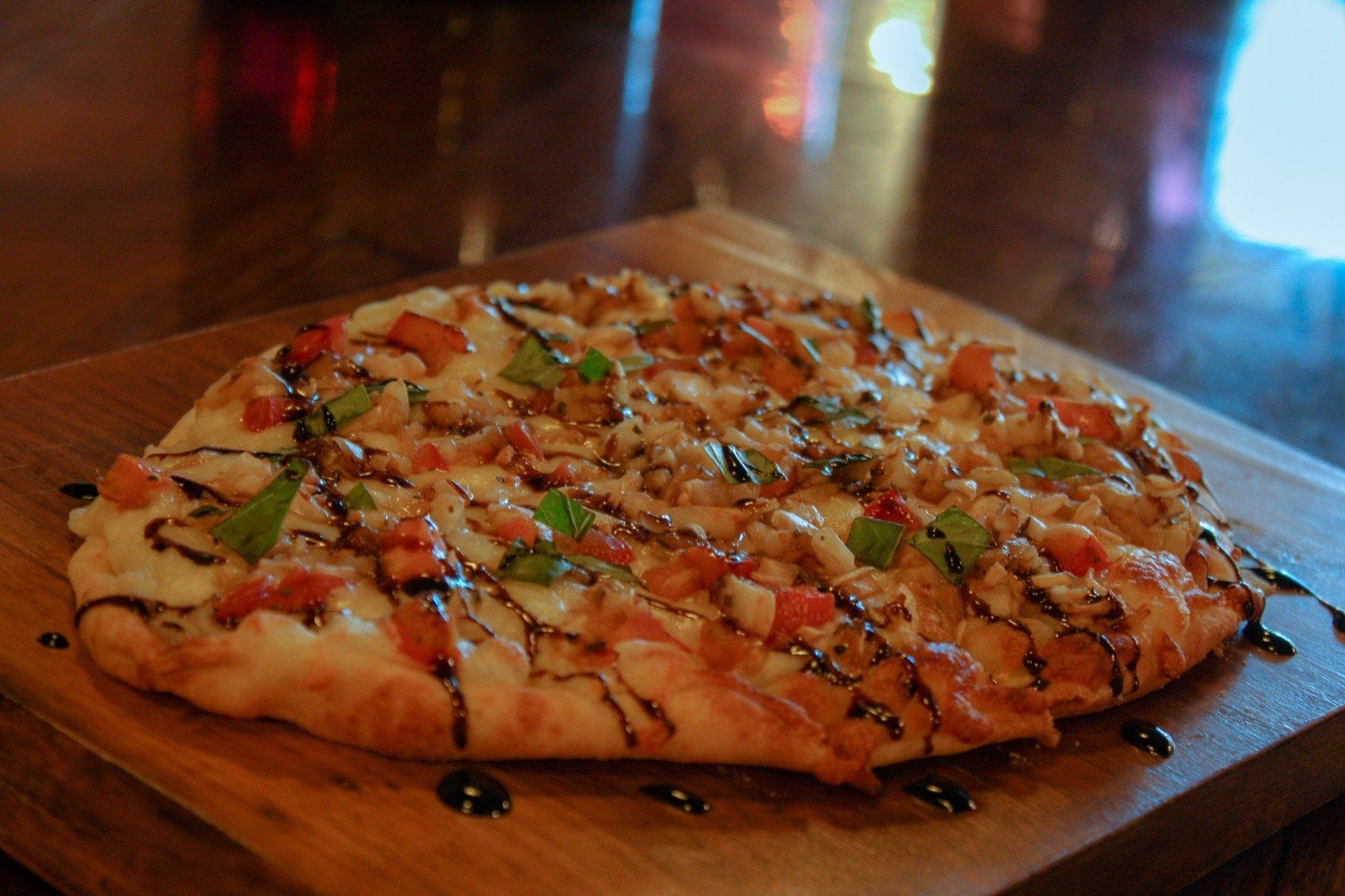 A pizza is sitting on a wooden cutting board on a table.