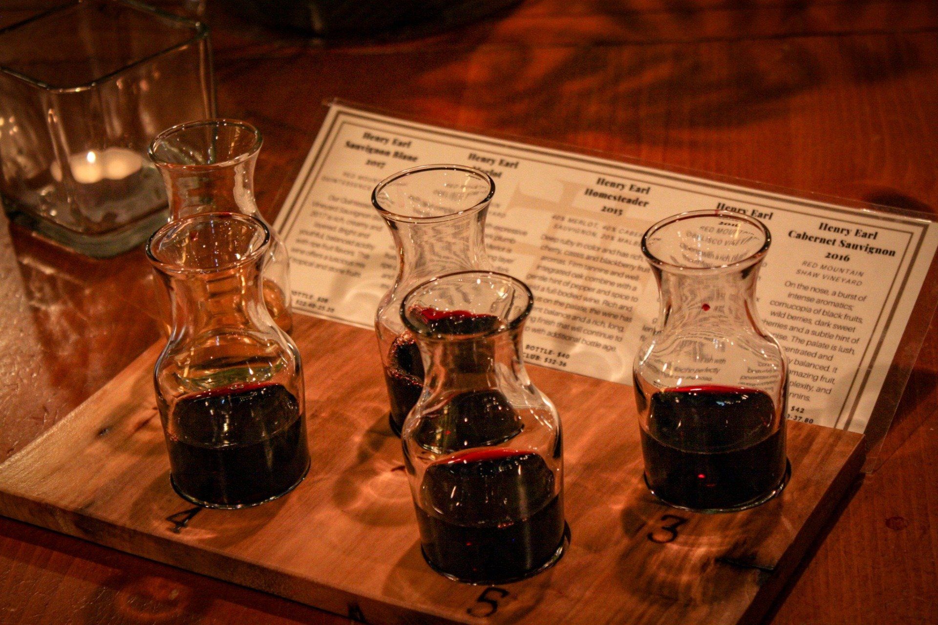 A wooden tray with four bottles of wine on it.