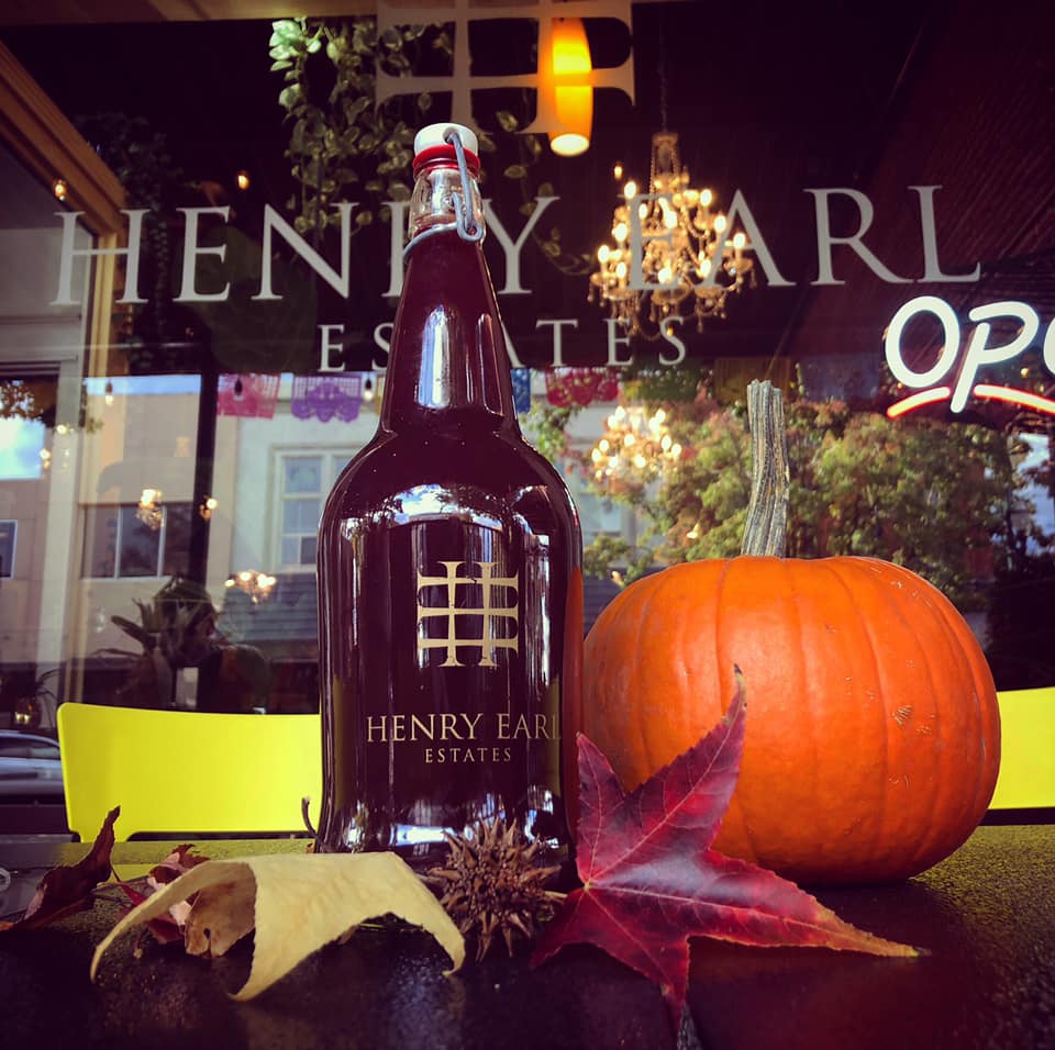 A bottle of henry earl sits on a table next to a pumpkin