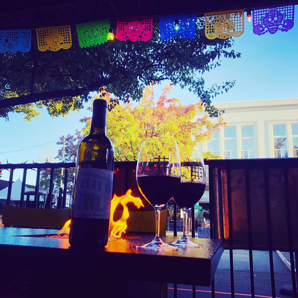 A bottle of wine sits on a table next to two glasses of wine