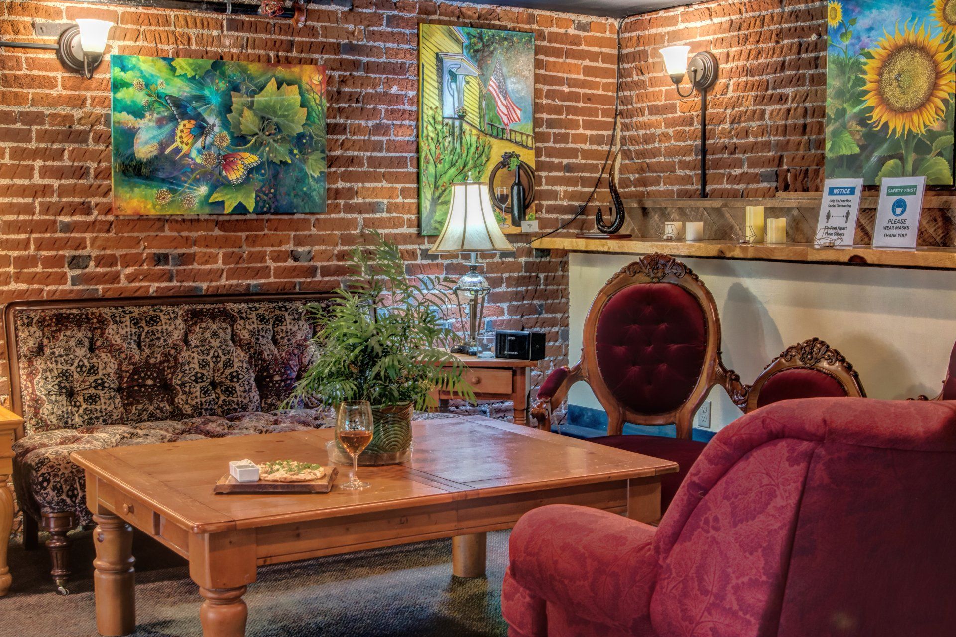 A living room with a couch , chair , table and paintings on the wall.