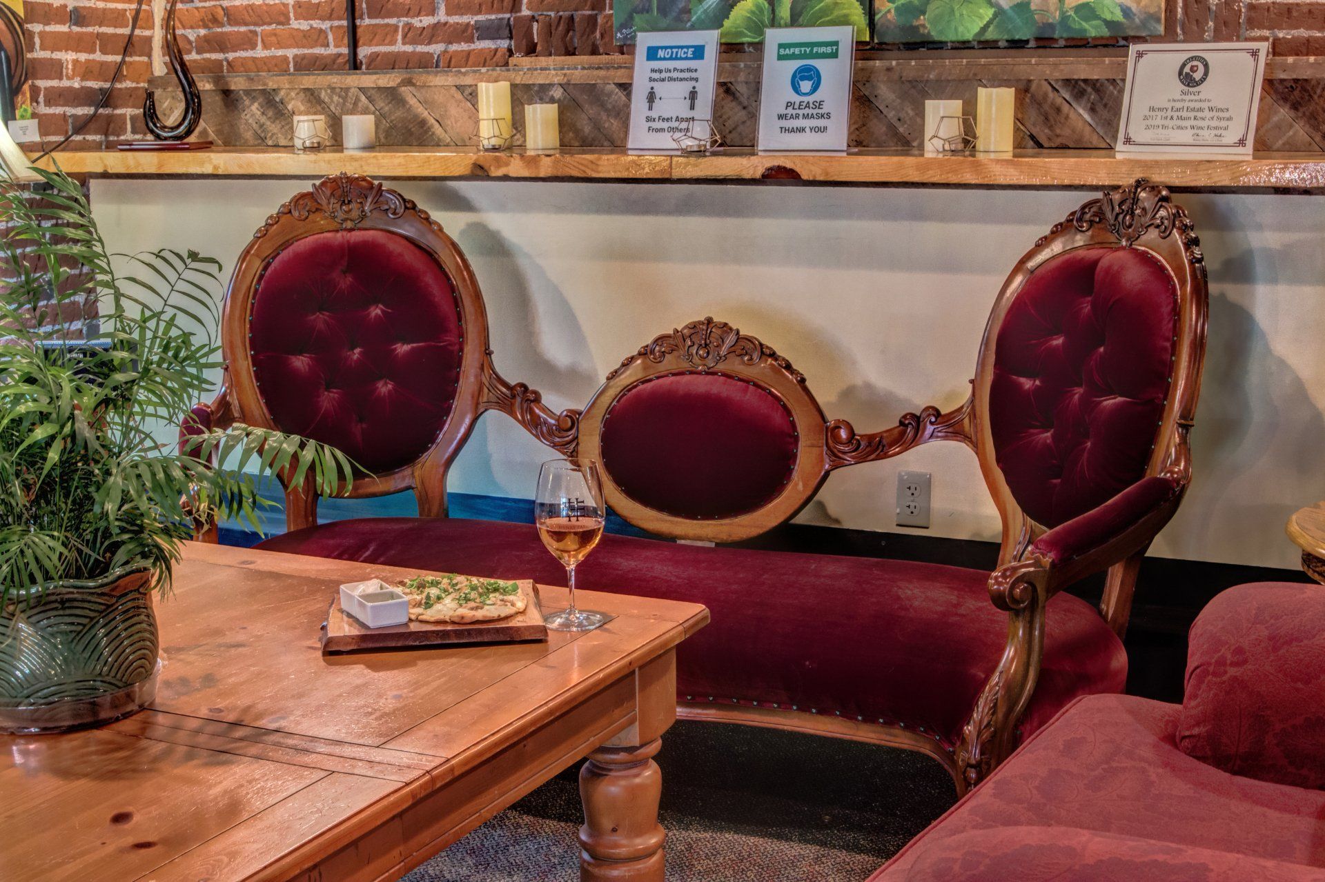 A living room with a couch and chairs and a table with a glass of wine on it.