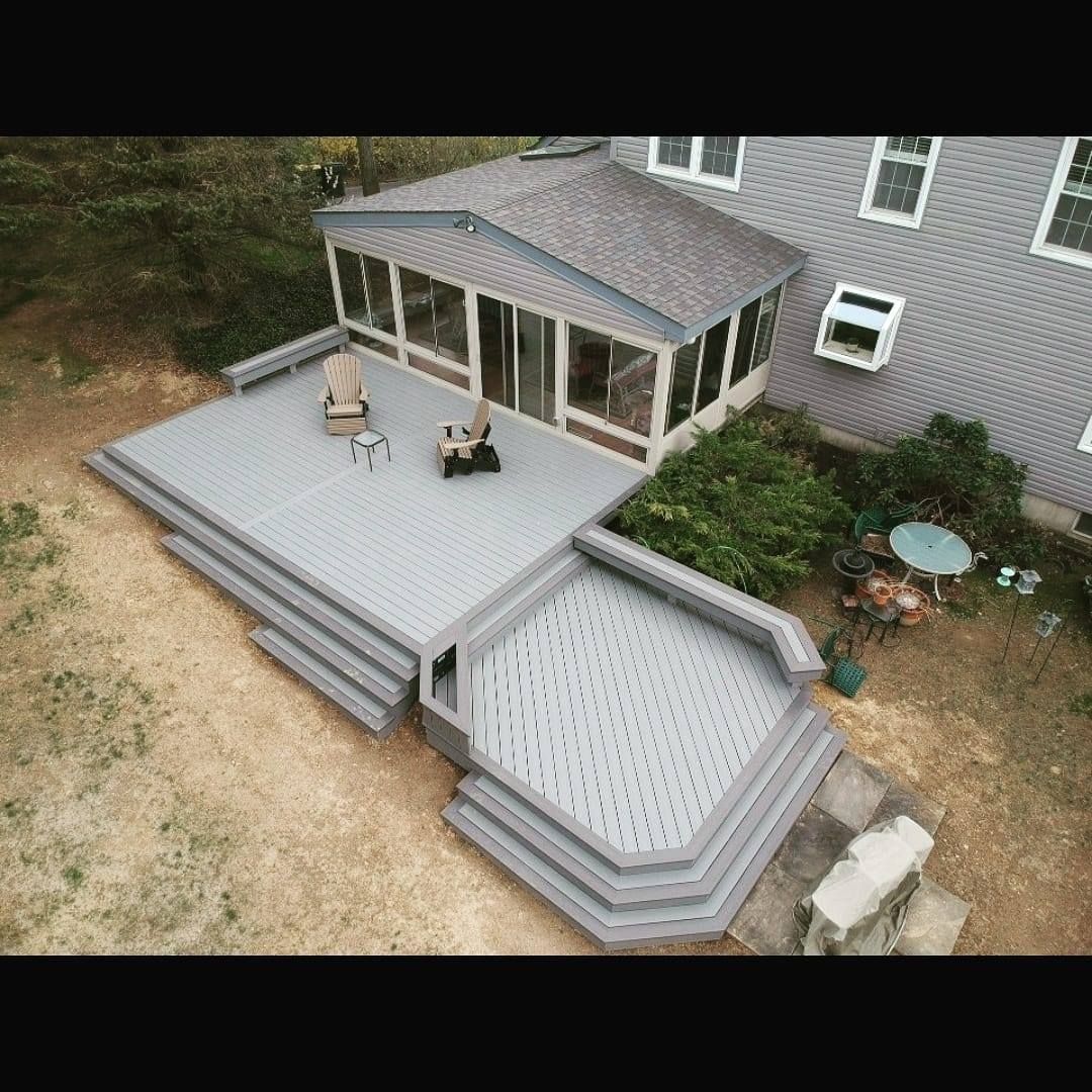 A large house with a large deck and a swimming pool in front of it.