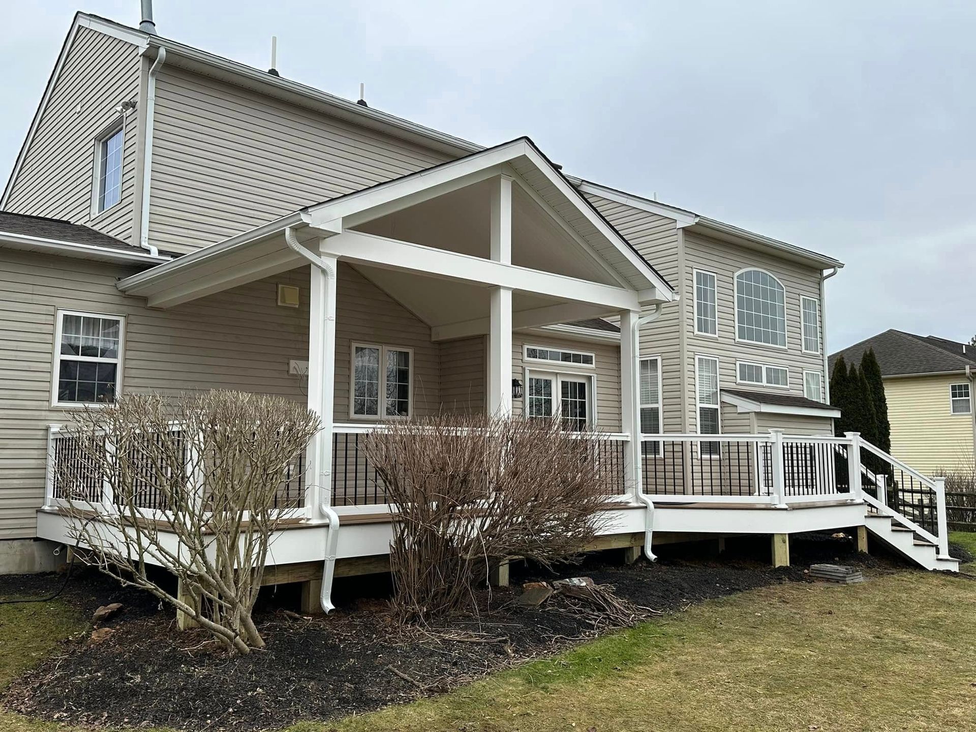 The back of a house with a large porch and stairs.