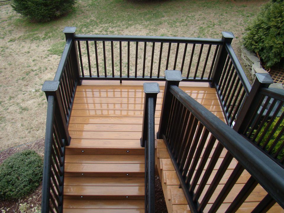 A wooden deck with stairs and a black railing