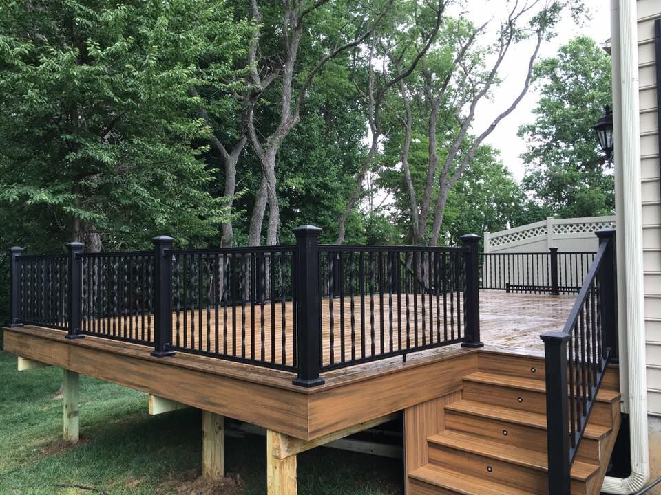 A wooden deck with stairs and a black railing
