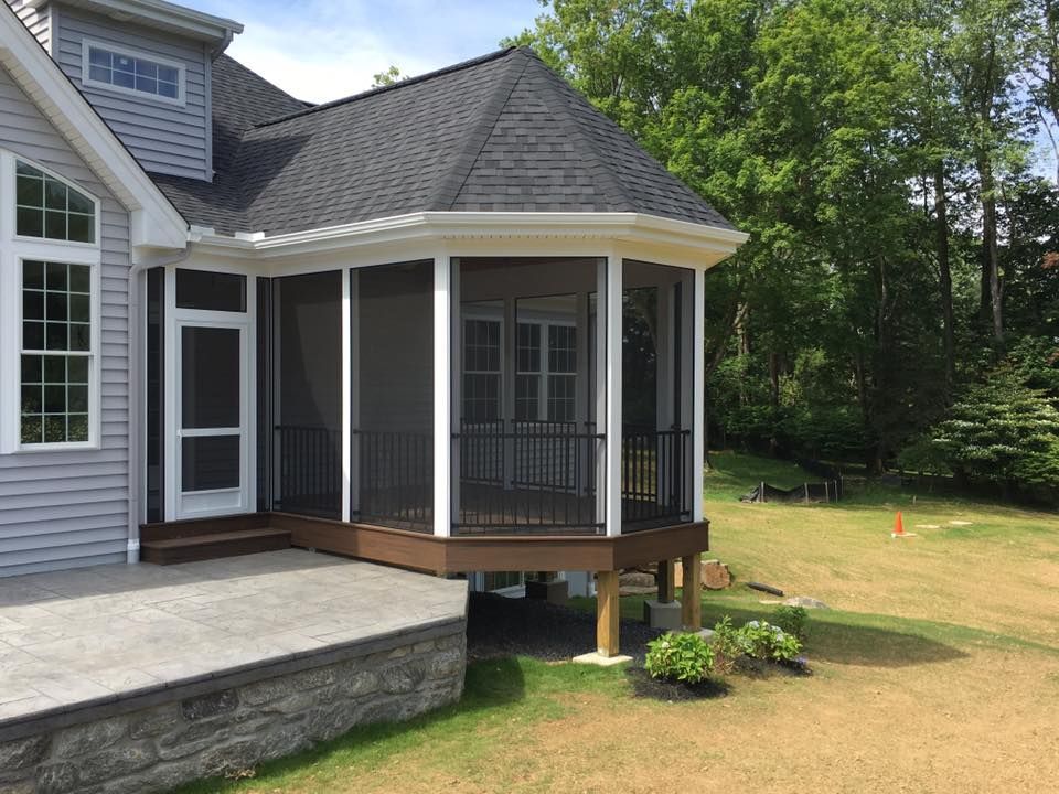 A screened in porch on the side of a house.