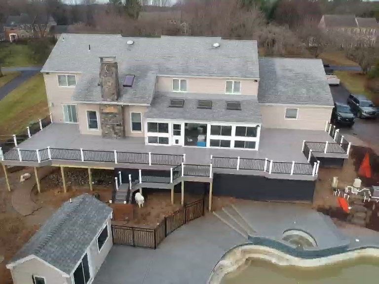 An aerial view of a large house with a large deck and a pool.