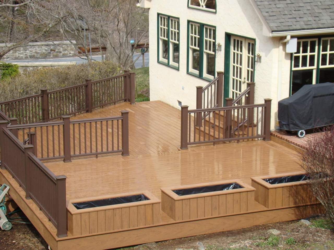 A white house with a large deck and planters in front of it