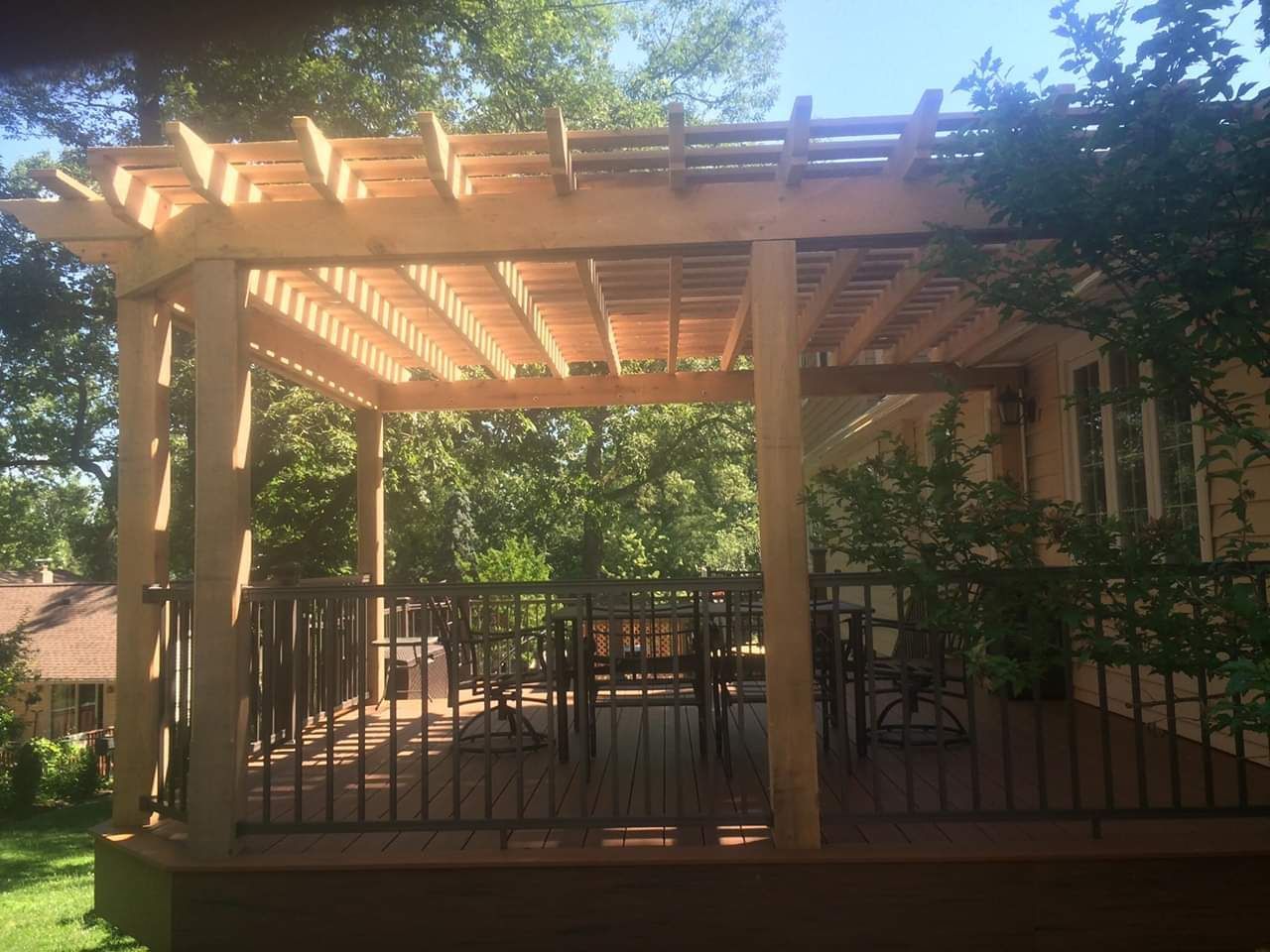 A wooden pergola is sitting on top of a wooden deck.