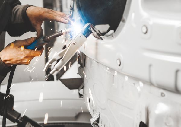 A man is welding a car in a garage.