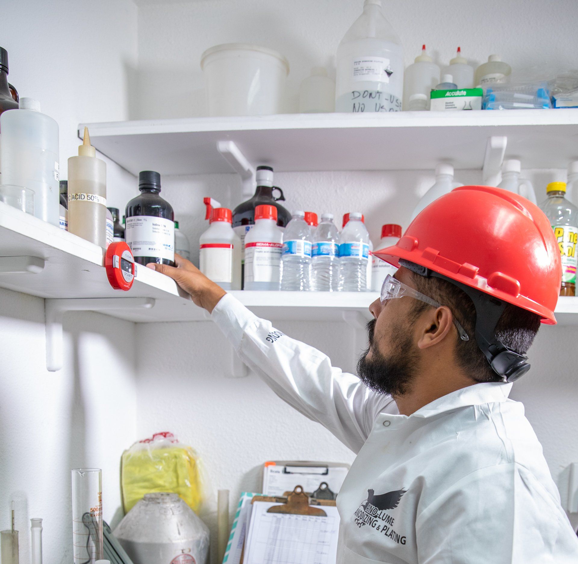 man reaching for chemicals on shelf above head