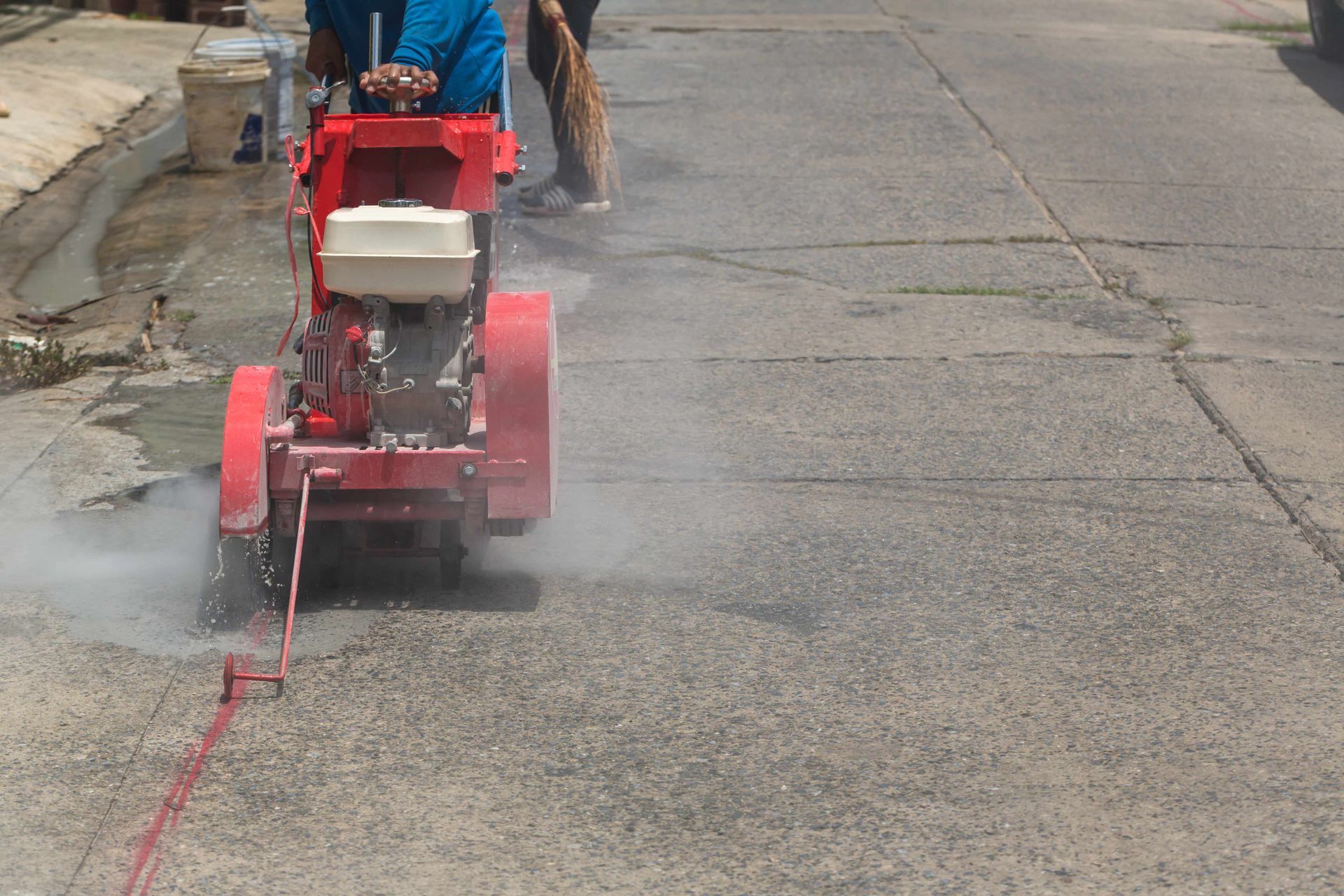 A man with a machine cutting concrete