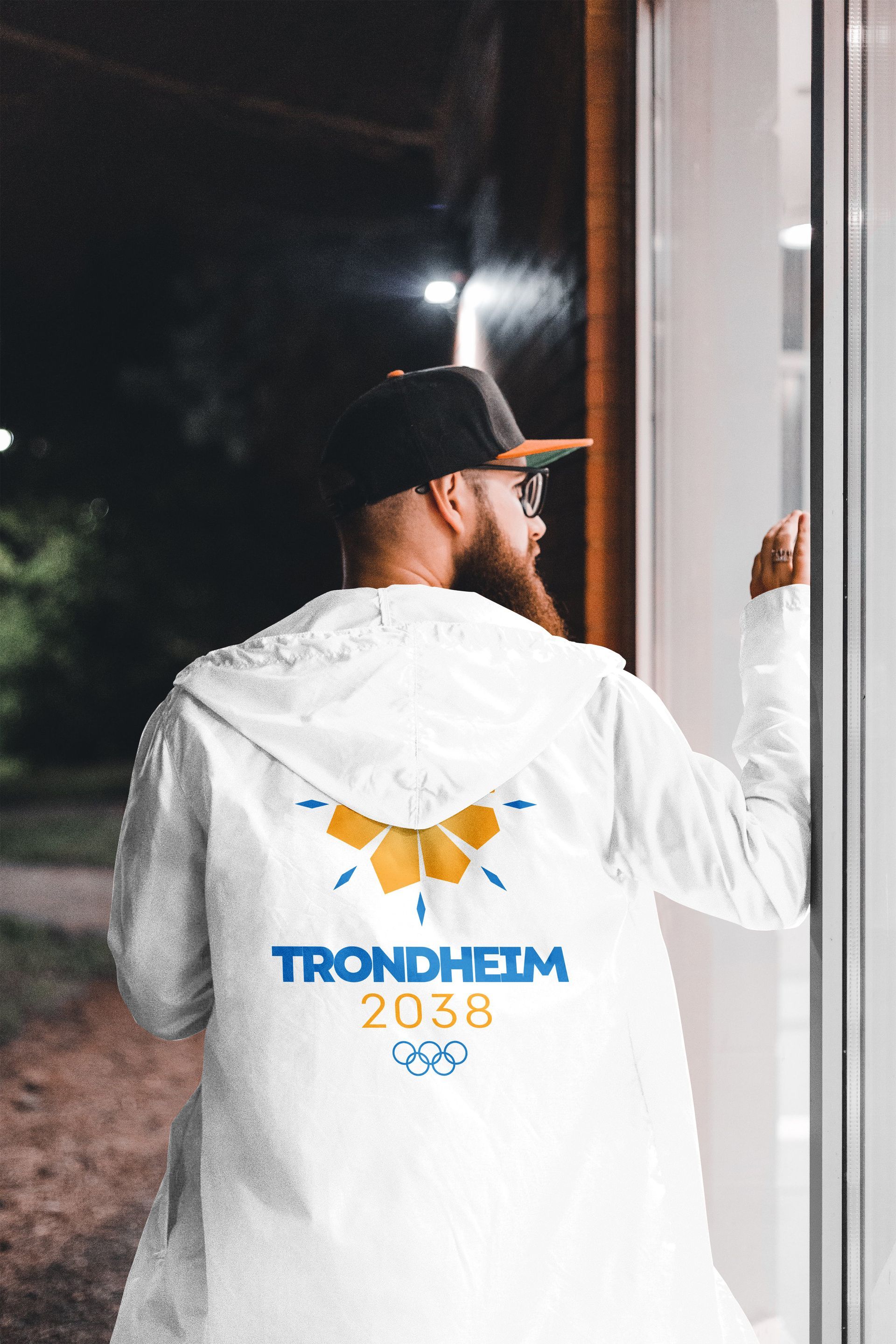 Person in white jacket with “Trondheim 2038” logo, standing by a doorway at night