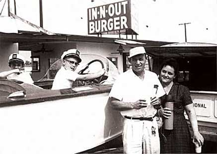 Vintage In-N-Out Burger stand with employees serving smiling customers at a drive-in counter