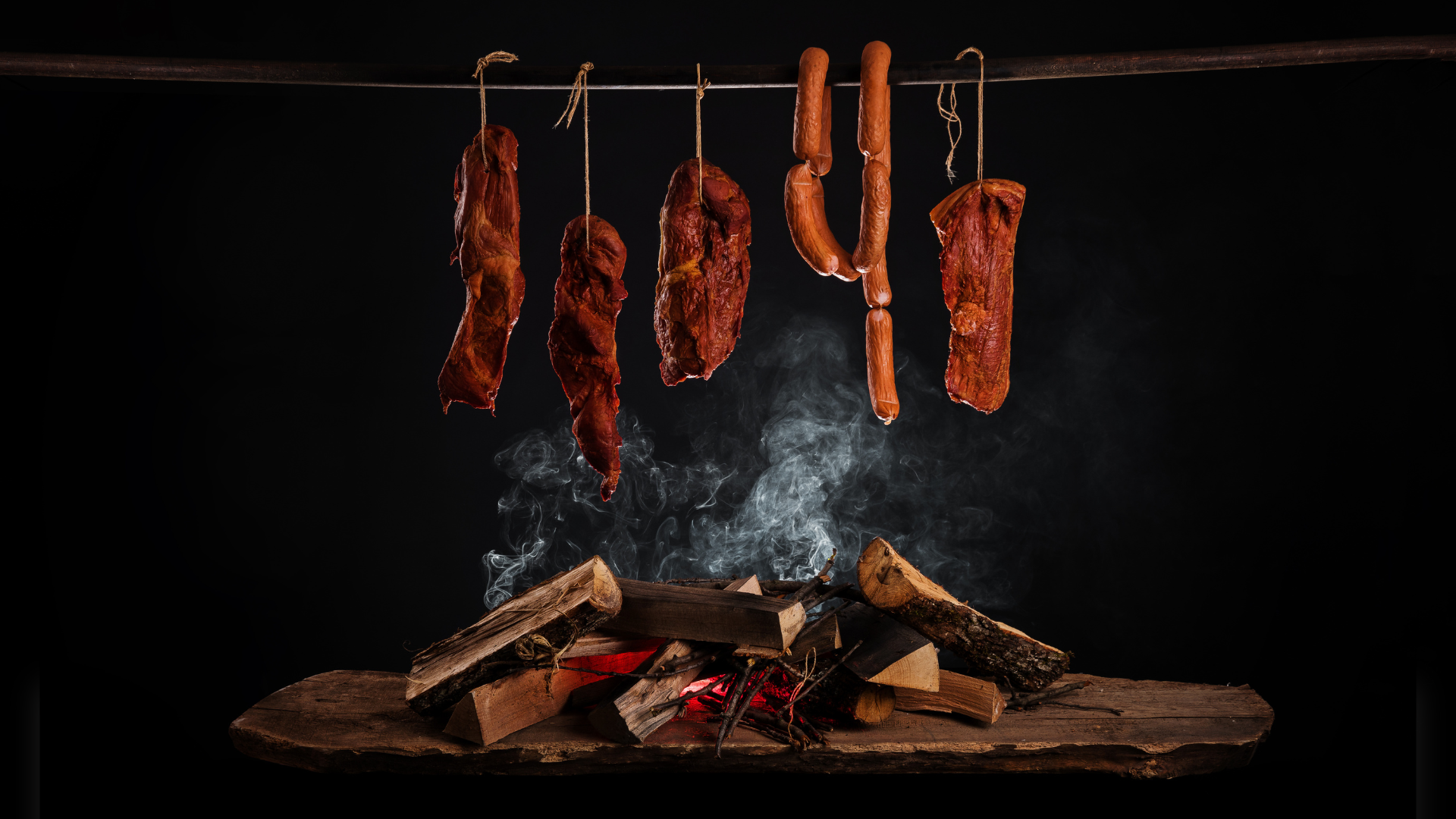 A bunch of meat hanging from a hook over a fire.