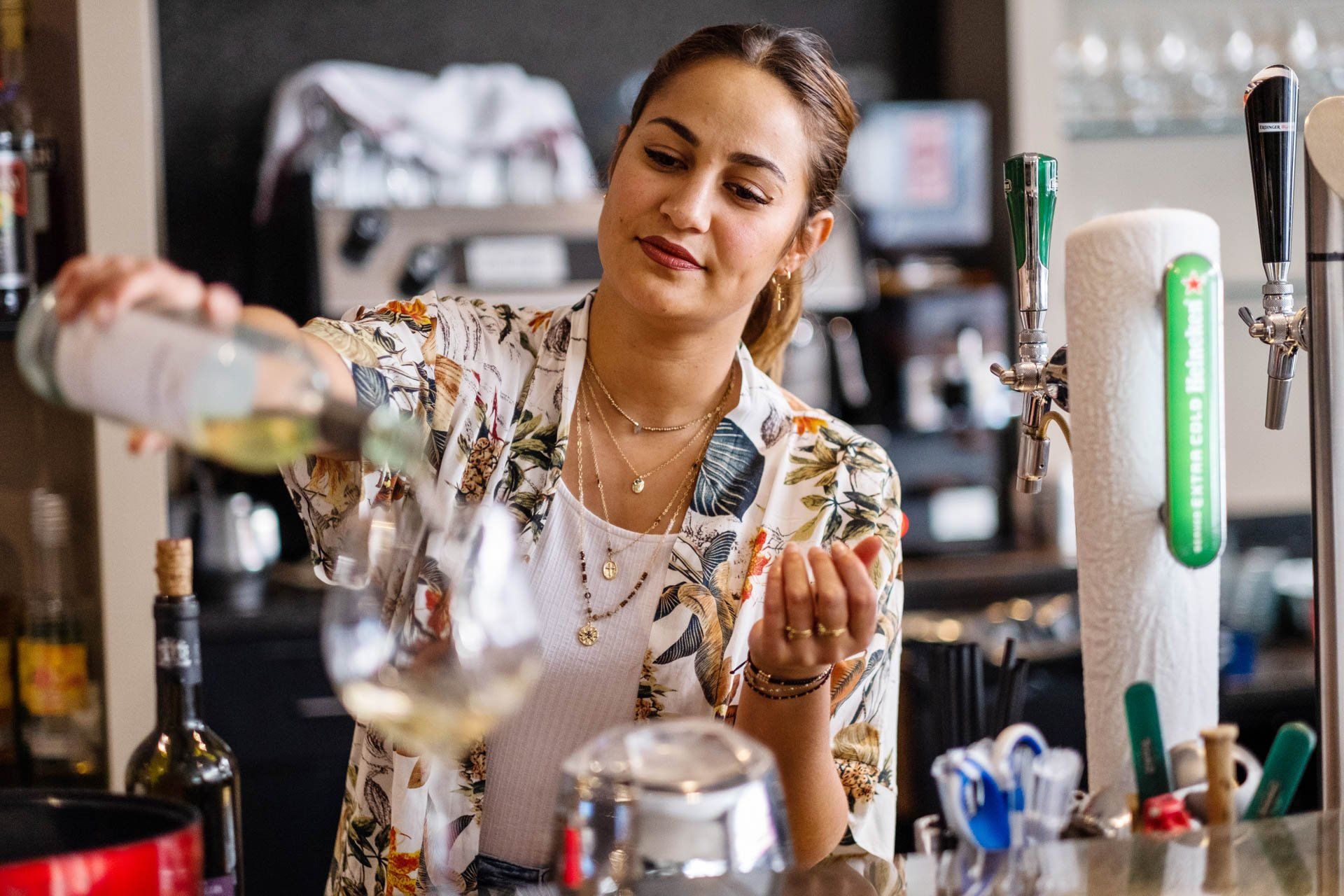 Une femme verse du vin dans un verre dans un bar.