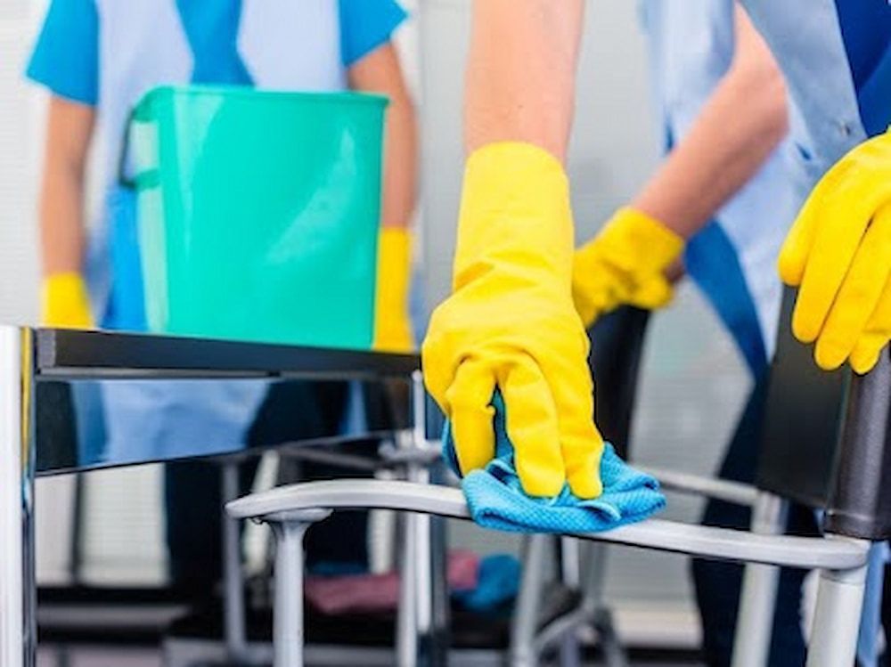 A Person Wearing Yellow Gloves Is Cleaning A Chair — Alta Cleaning Service In Coconut Grove, NT