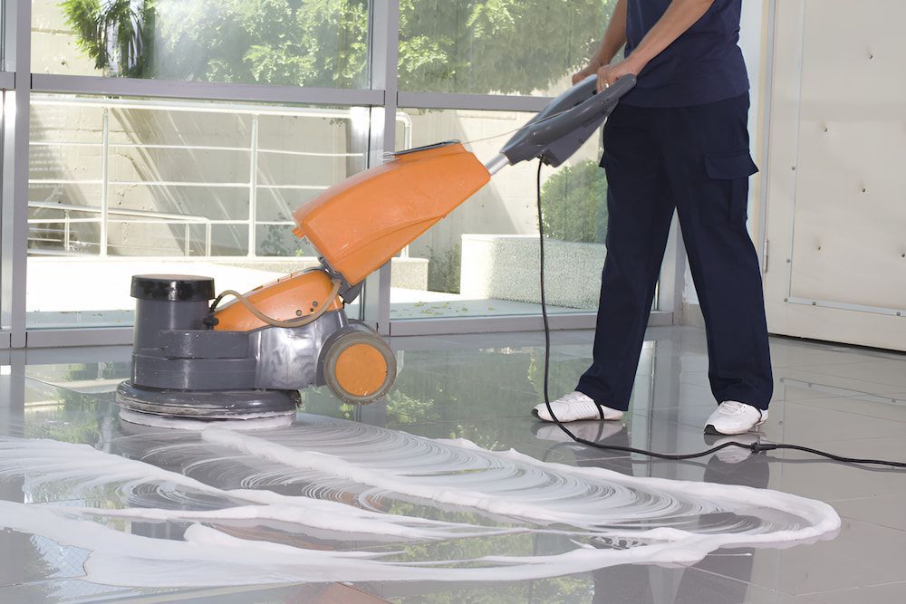 A Woman Is Cleaning The Floor With A Machine — Alta Cleaning Service In Coconut Grove, NT