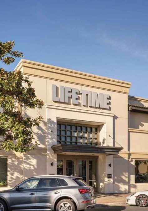 A car is parked in front of a lifetime building.
