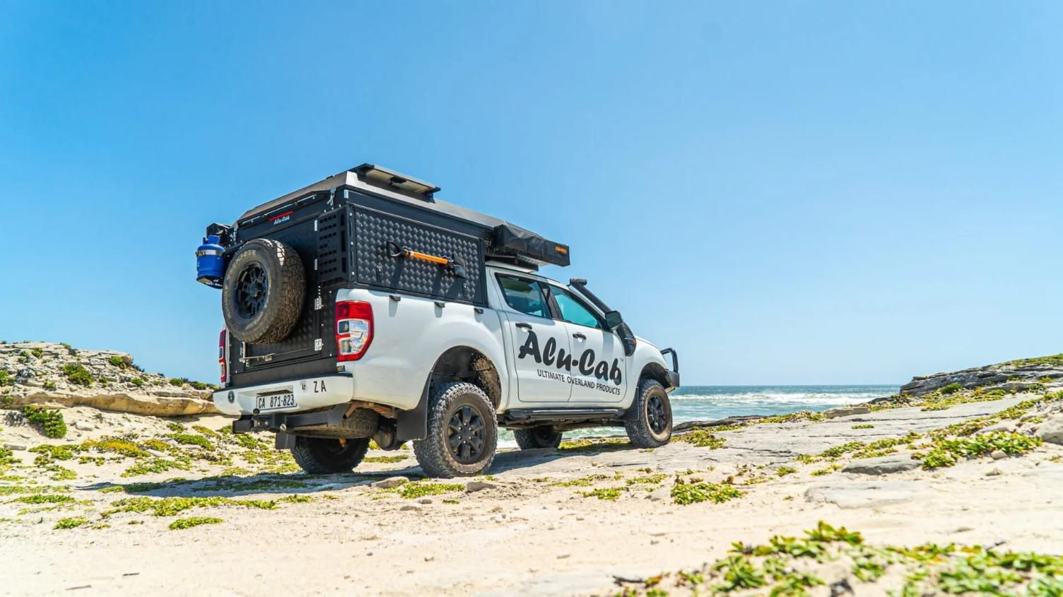 A White Truck is Parked on a Sandy Beach Next to the Ocean — Whitsunday 4x4 & Automotive In Cannonvale, QLD