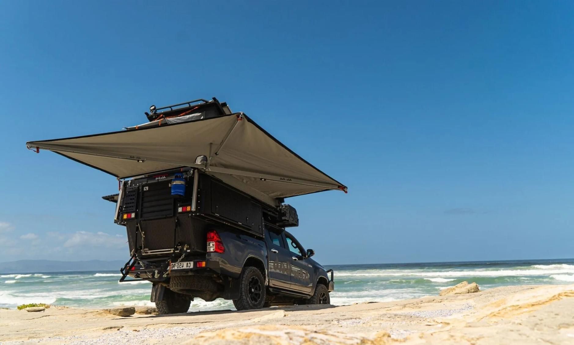 A Truck With an Awning on Top of It is Parked on the Beach — Whitsunday 4x4 & Automotive In Cannonvale, QLD