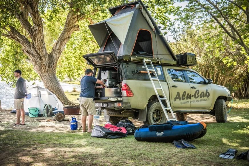 A Man is Standing Next to a Truck With a Tent on Top of It — Whitsunday 4x4 & Automotive In Cannonvale, QLD