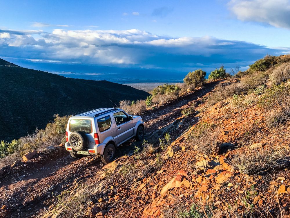 A Black SUV is Driving Down a Dirt Road in the Woods — Whitsunday 4x4 & Automotive In Cannonvale, QLD