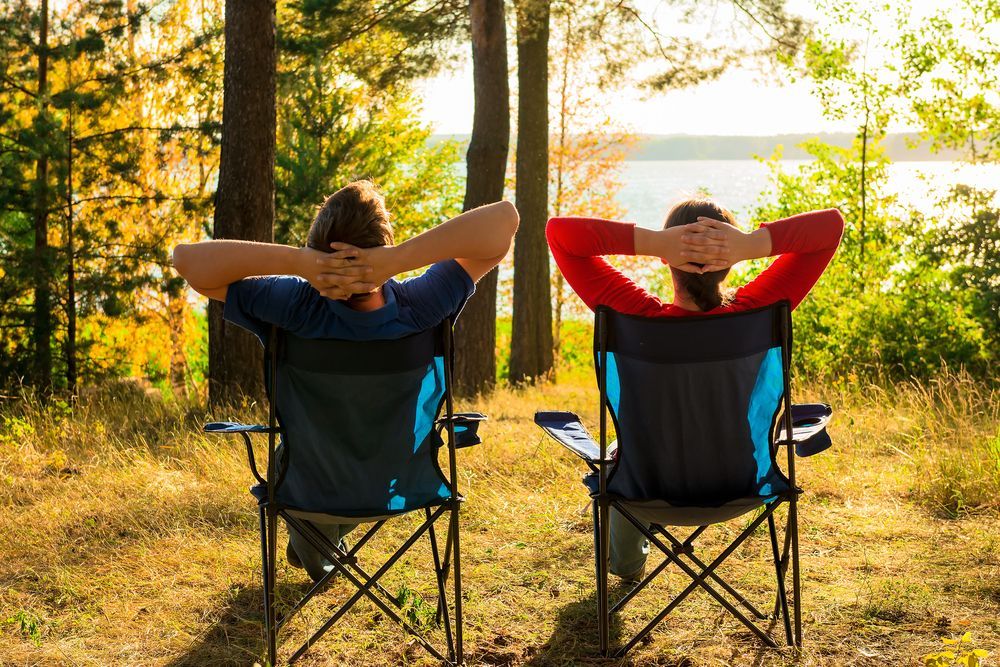 A man and a woman are sitting in folding chairs in the woods - Whitsunday 4x4 & Automotive In Cannonvale, QLD