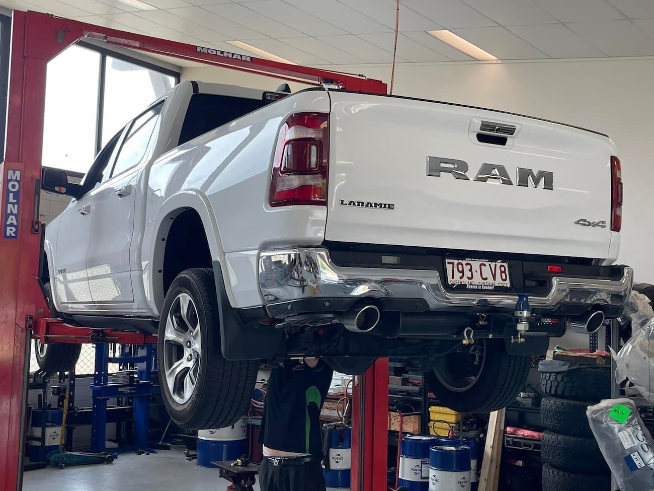 A White Ram Truck is Sitting on a Lift in a Garage — Whitsunday 4x4 & Automotive In Cannonvale, QLD