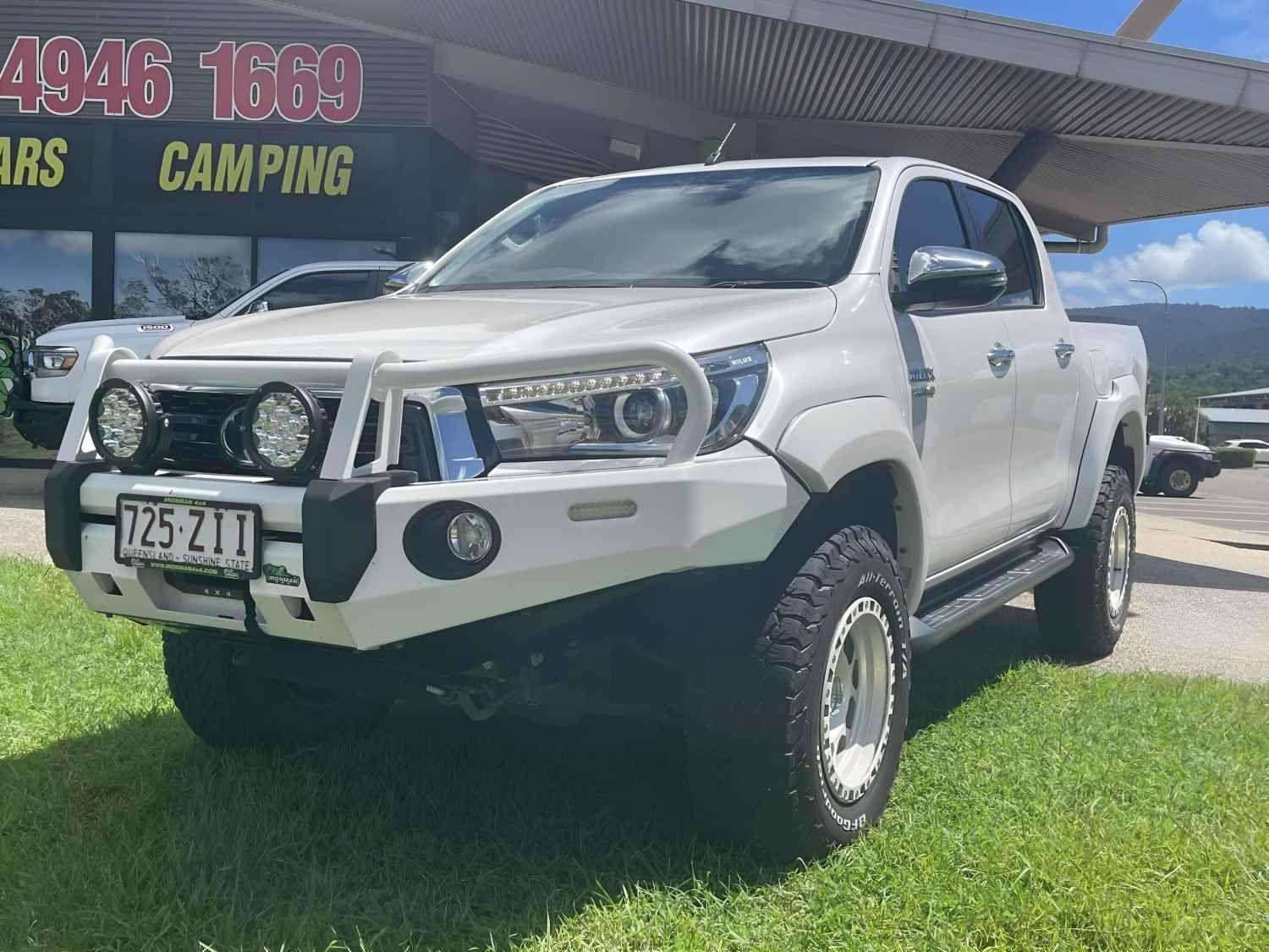 A White Truck is Parked in the Grass in Front of a Building — Whitsunday 4x4 & Automotive In Cannonvale, QLD