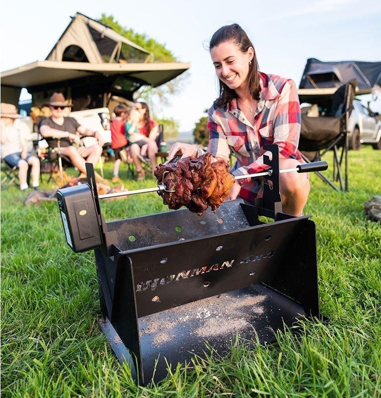 A woman is cooking meat on a grill in the grass - Whitsunday 4x4 & Automotive In Cannonvale, QLD