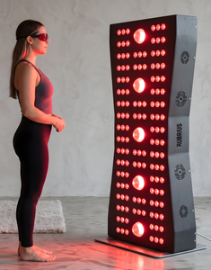Woman stands facing a red-lit vertical LED fitness machine in a studio.