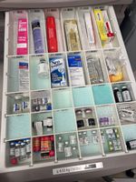 Drawer filled with various medical supplies and medications, organized in compartments.