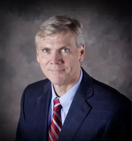 A man in a suit and tie is smiling for the camera