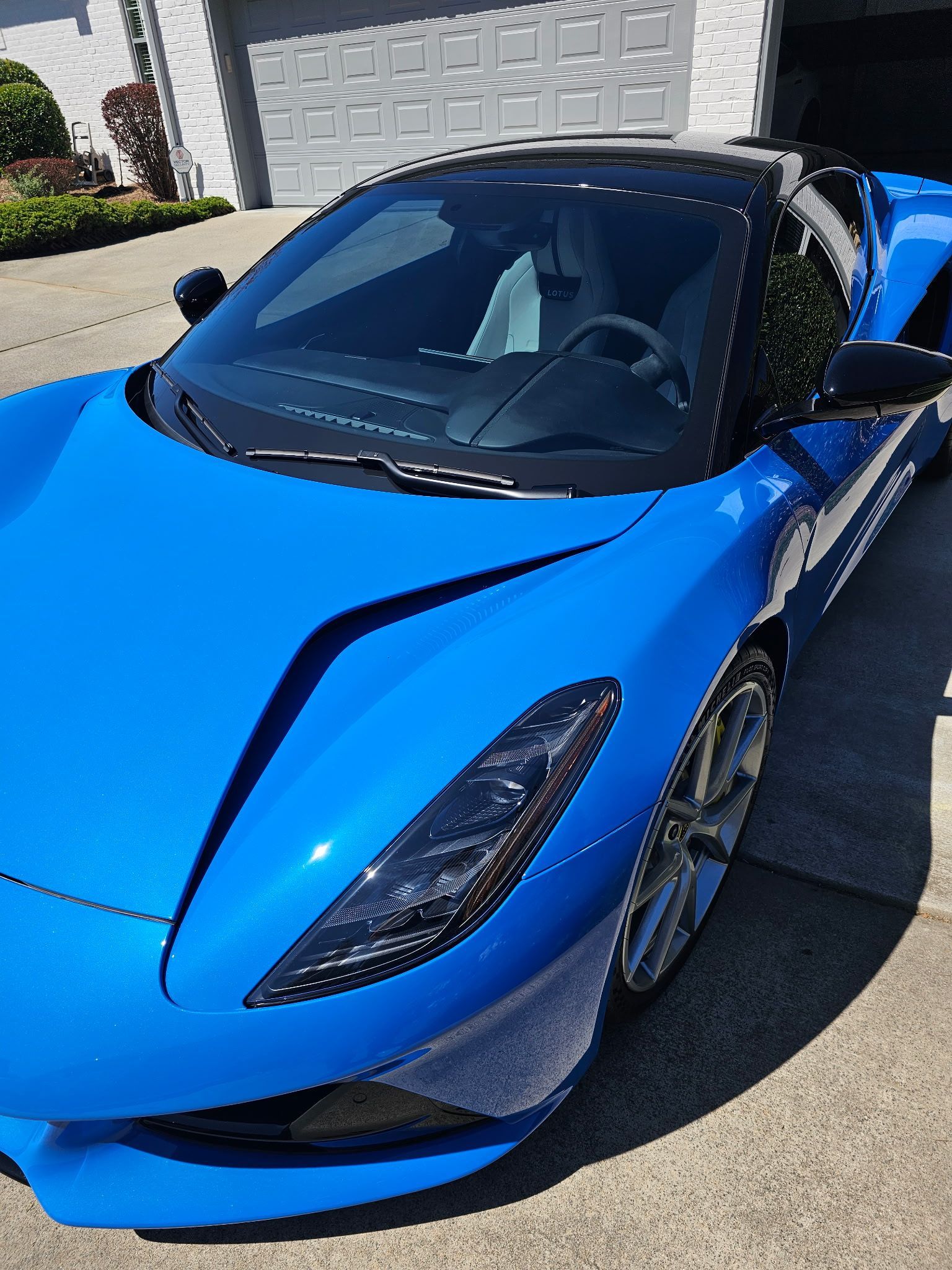 Blue McLaren sports car parked in front of a house.