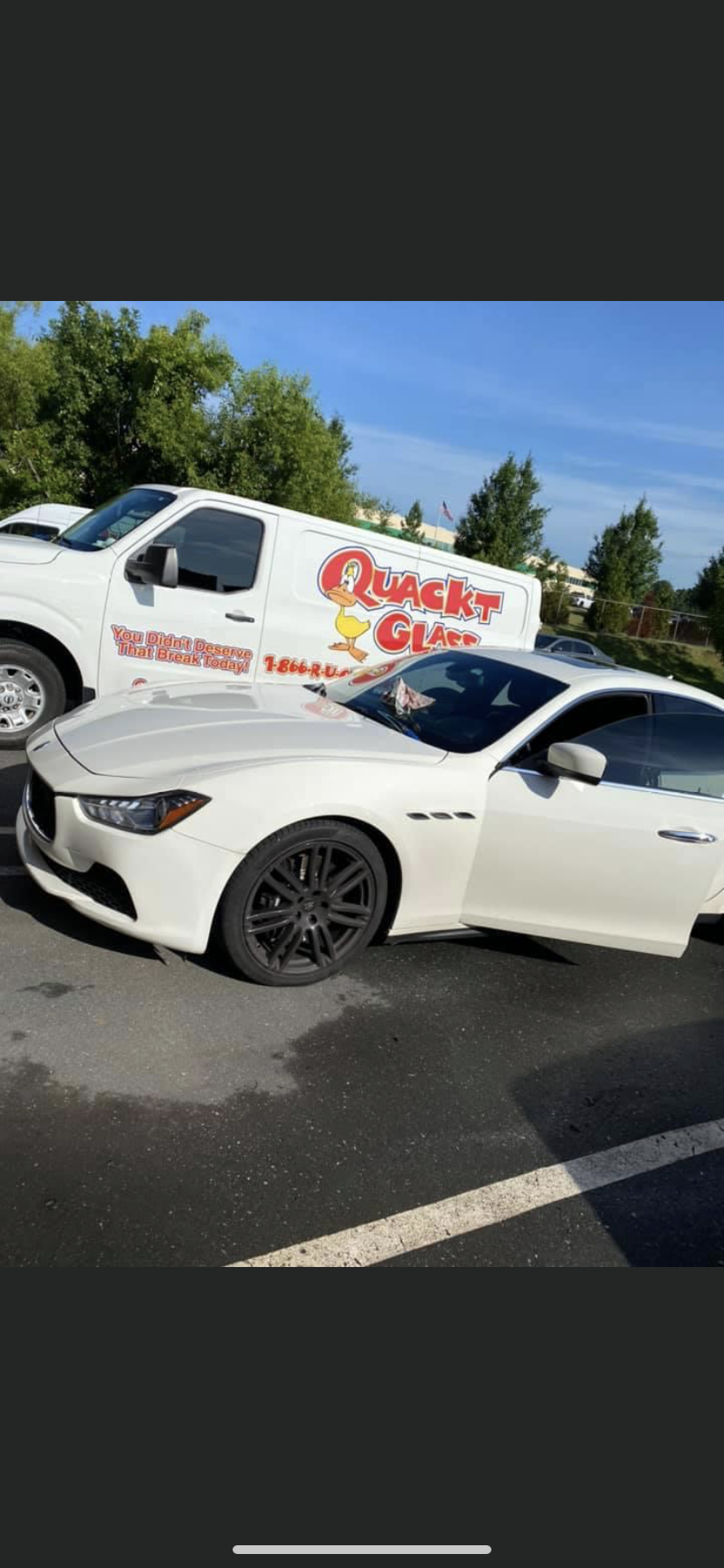 White Maserati car parked next to a Quick Glass service van on an asphalt surface.