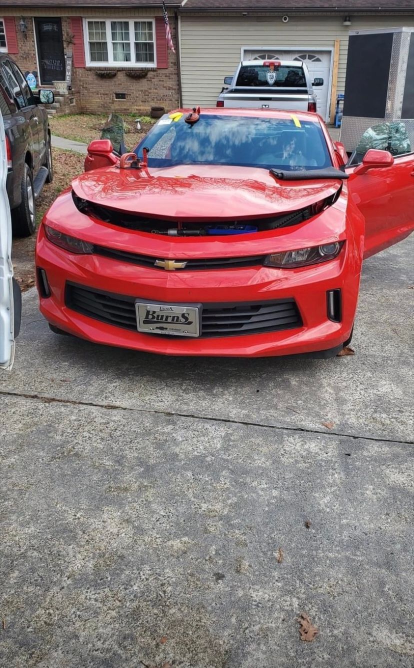Red Chevrolet Camaro with its hood and driver's side door open, parked on a driveway.