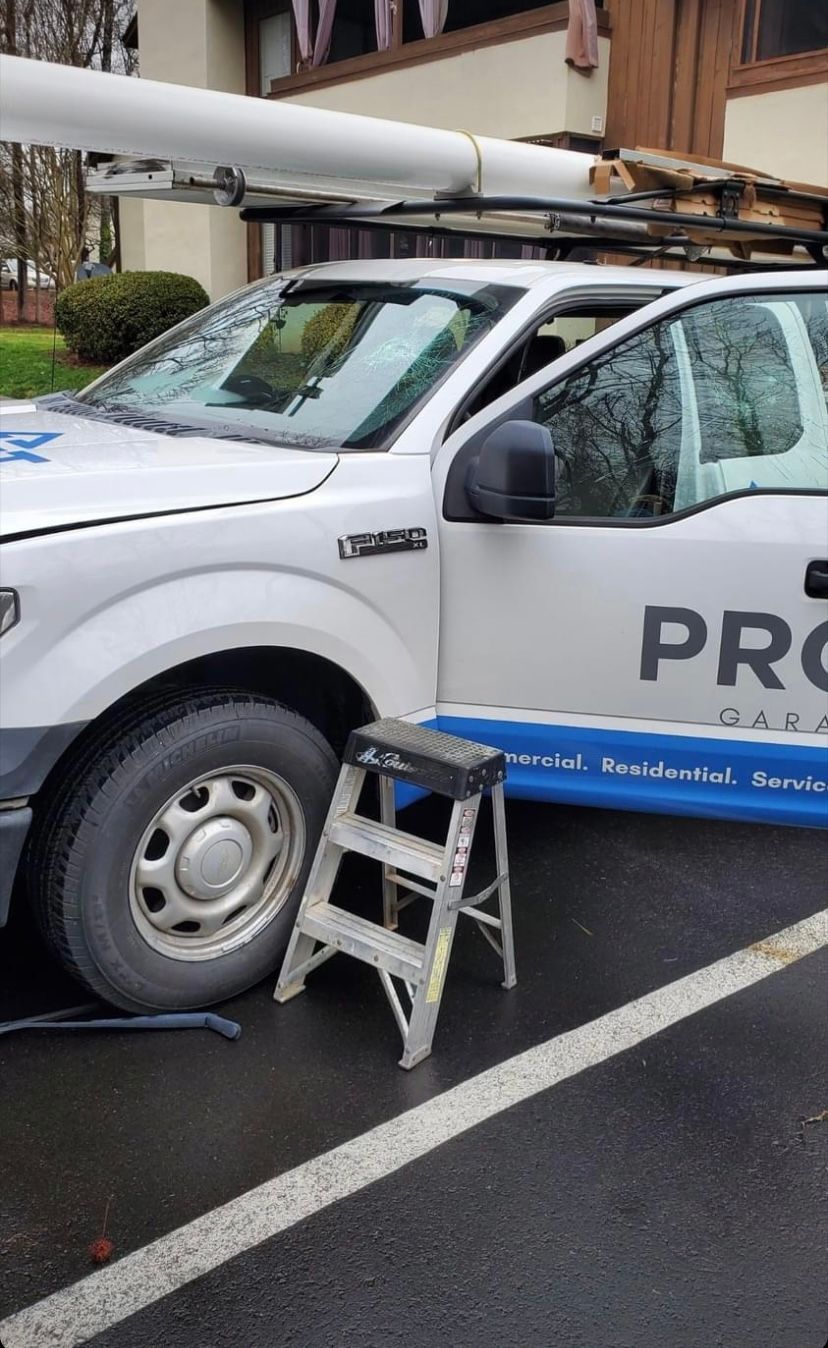 White work truck with open door, ladder, and equipment on roof.