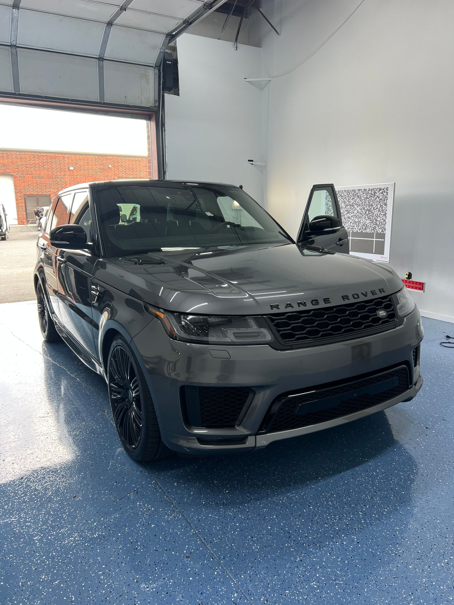 Gray Range Rover Sport SUV inside a garage with its door open.