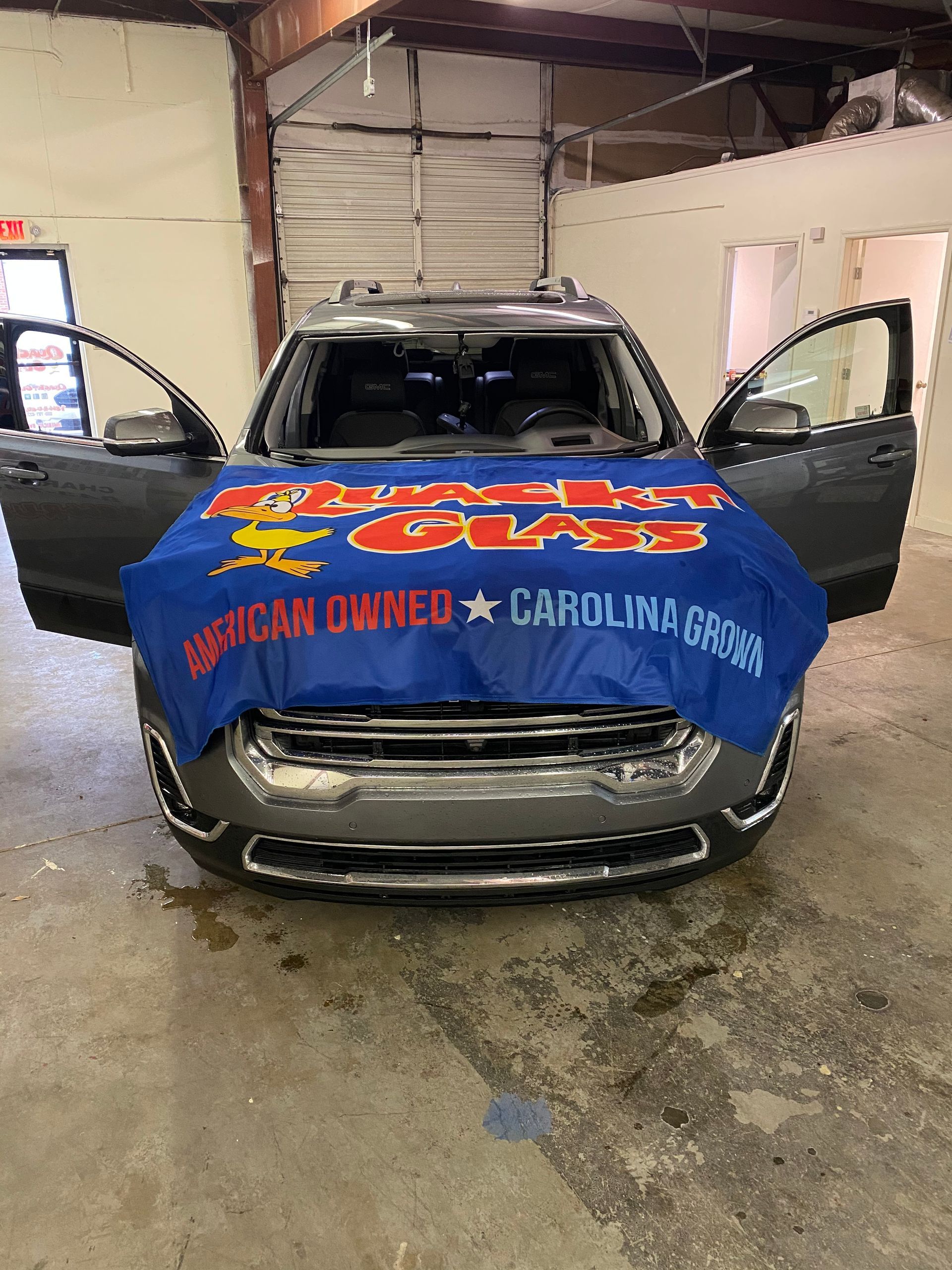 Car with open doors, covered by blue banner reading 