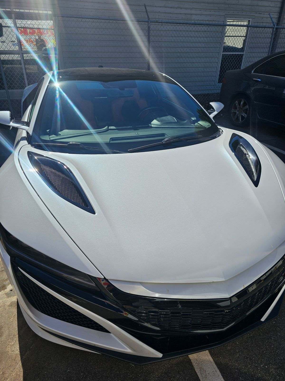 White Acura NSX sports car parked outdoors on a sunny day.