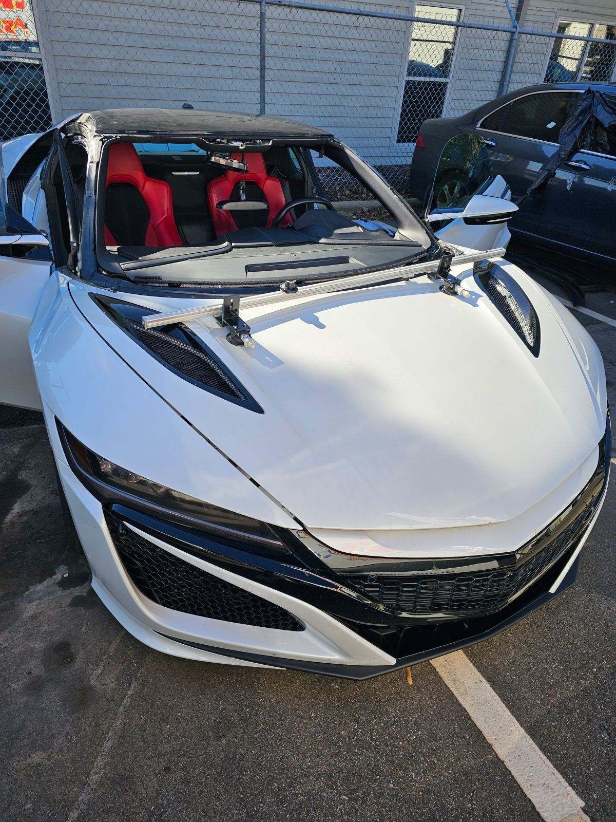 White sports car with red interior, parked outside.
