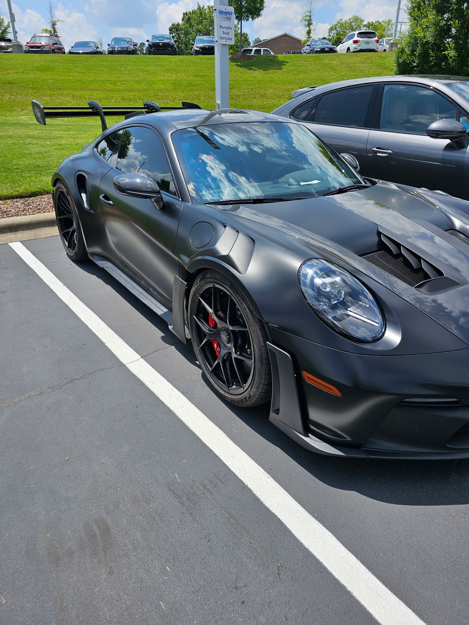 Black Porsche sports car parked in a parking lot on a sunny day.
