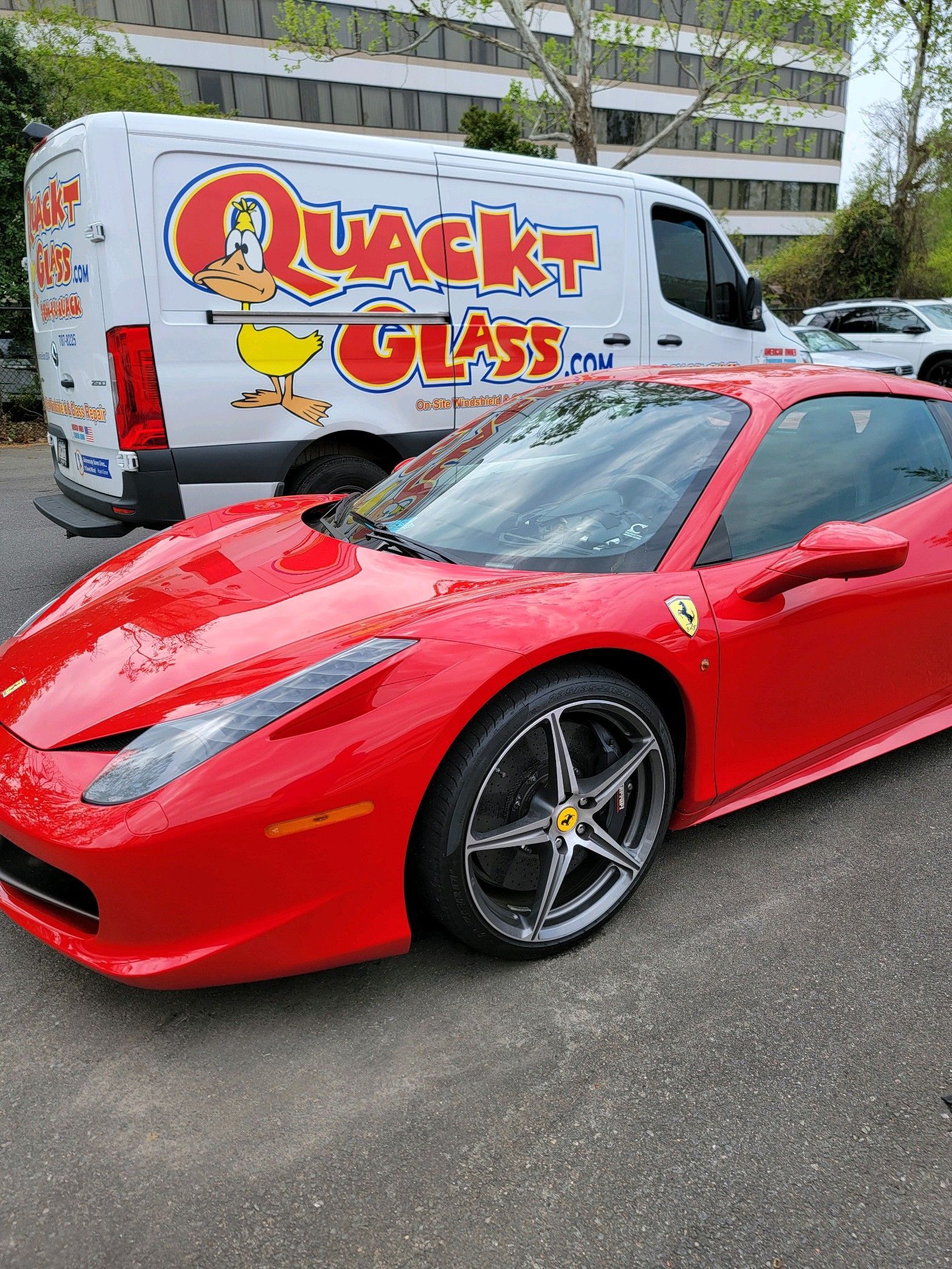 Red Ferrari next to a Quackt Glass service van.