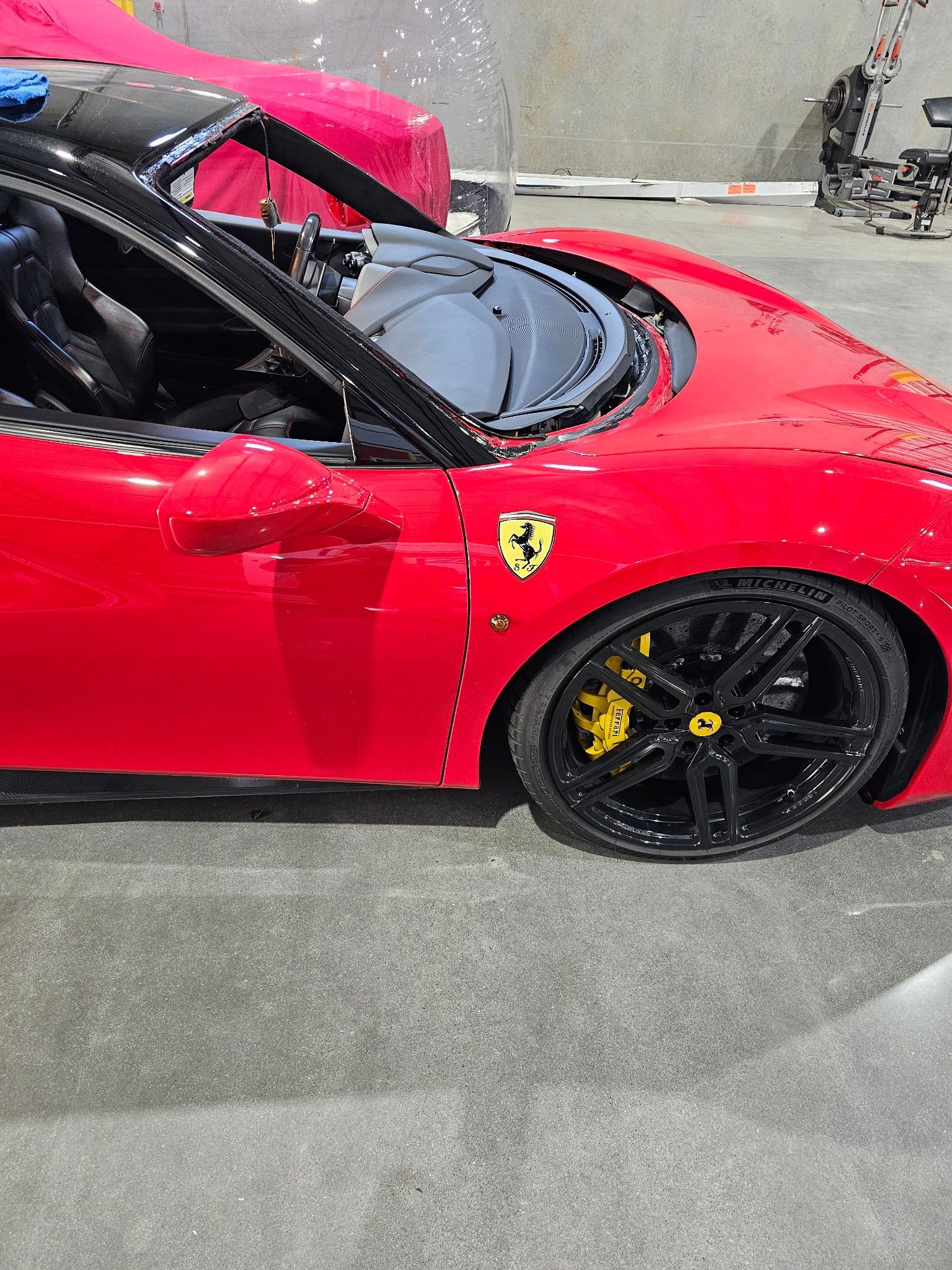 Red Ferrari sports car with black wheels and yellow brake calipers.